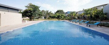 Una piscina con sillas de descanso y palmeras.