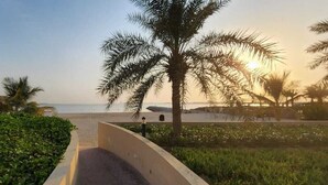 A pathway leading to a beach with palm trees and a clear view of the ocean. - Czechin - Kahraman Building (Ras Al Khaimah)