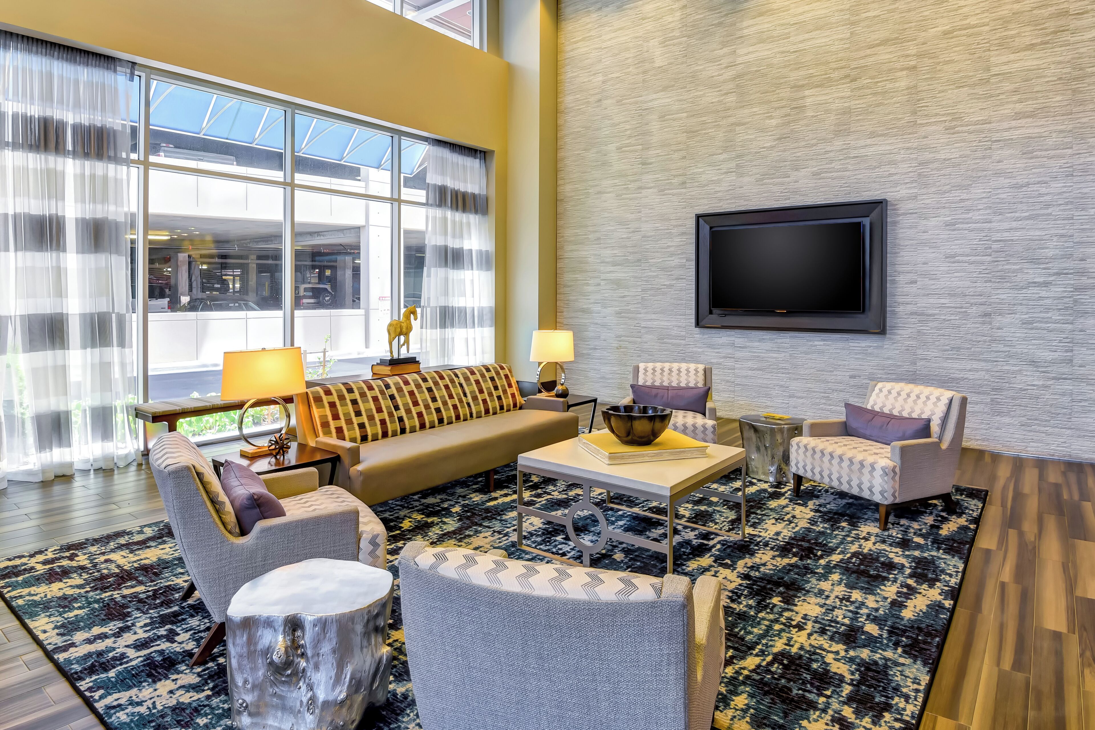 A modern living room with a sofa, armchairs, a coffee table, and a TV mounted on the wall.