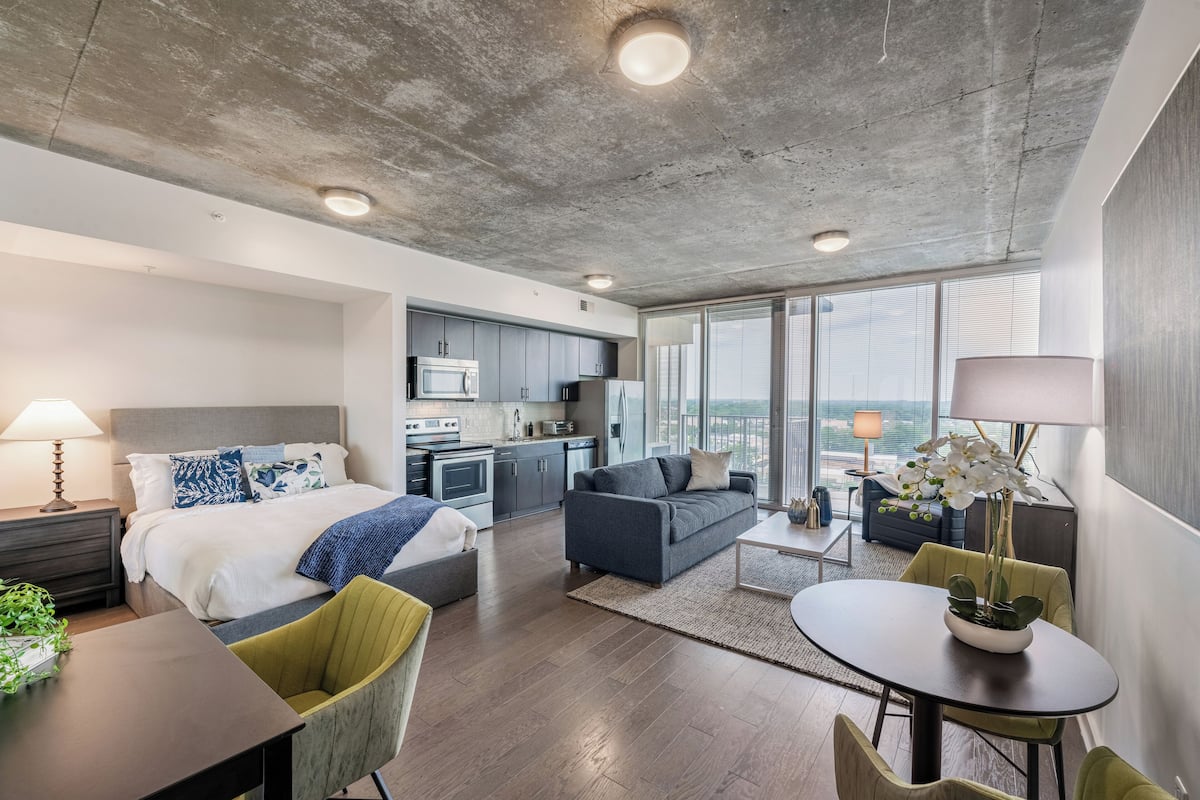 Une chambre d’hôtel moderne dotée d’un grand lit, d’un canapé, d’une table à manger et d’un coin cuisine.