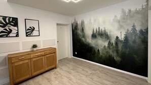 Een kamer met een grote boswandeling, een houten kast en twee ingelijste foto's aan de muur.
