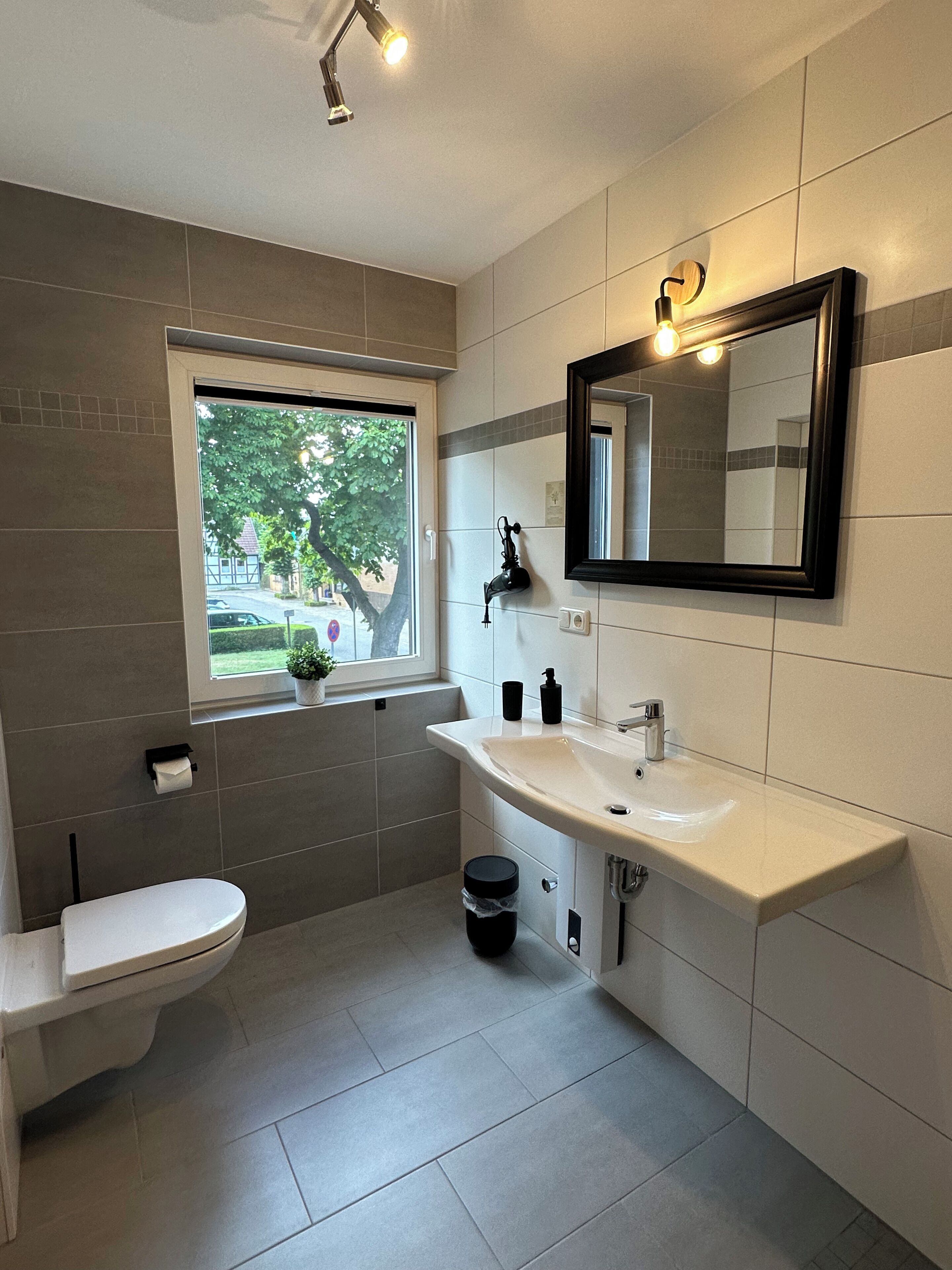 Un baño moderno con inodoro, lavamanos y ventana.