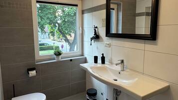 Un baño moderno con inodoro, lavamanos y ventana.