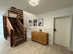 A staircase with wooden railings leading to a landing, a wooden cabinet with drawers, and three framed wall art pieces. - Meinpartments Wolfsburg (Wolfsburg)