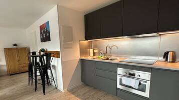 A modern kitchen with dark cabinets, a stainless steel sink, and a built-in oven.