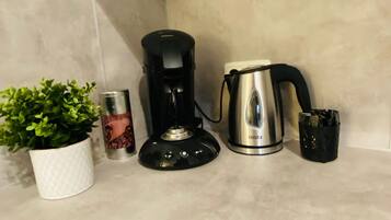 Eine Küchenarbeitsplatte mit Kaffeemaschine, Wasserkocher, Pflanze und einer Vorratsdose.