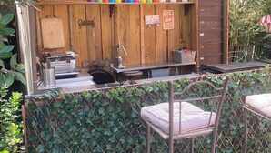 A rustic outdoor café with a wooden counter, metal chairs, and a sign indicating hot dogs. - Maison Familiale de Charme (Lège-Cap-Ferret)