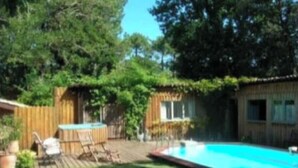 A backyard with a swimming pool, wooden deck, and a fenced area with a hot tub. - Maison Familiale de Charme (Lège-Cap-Ferret)