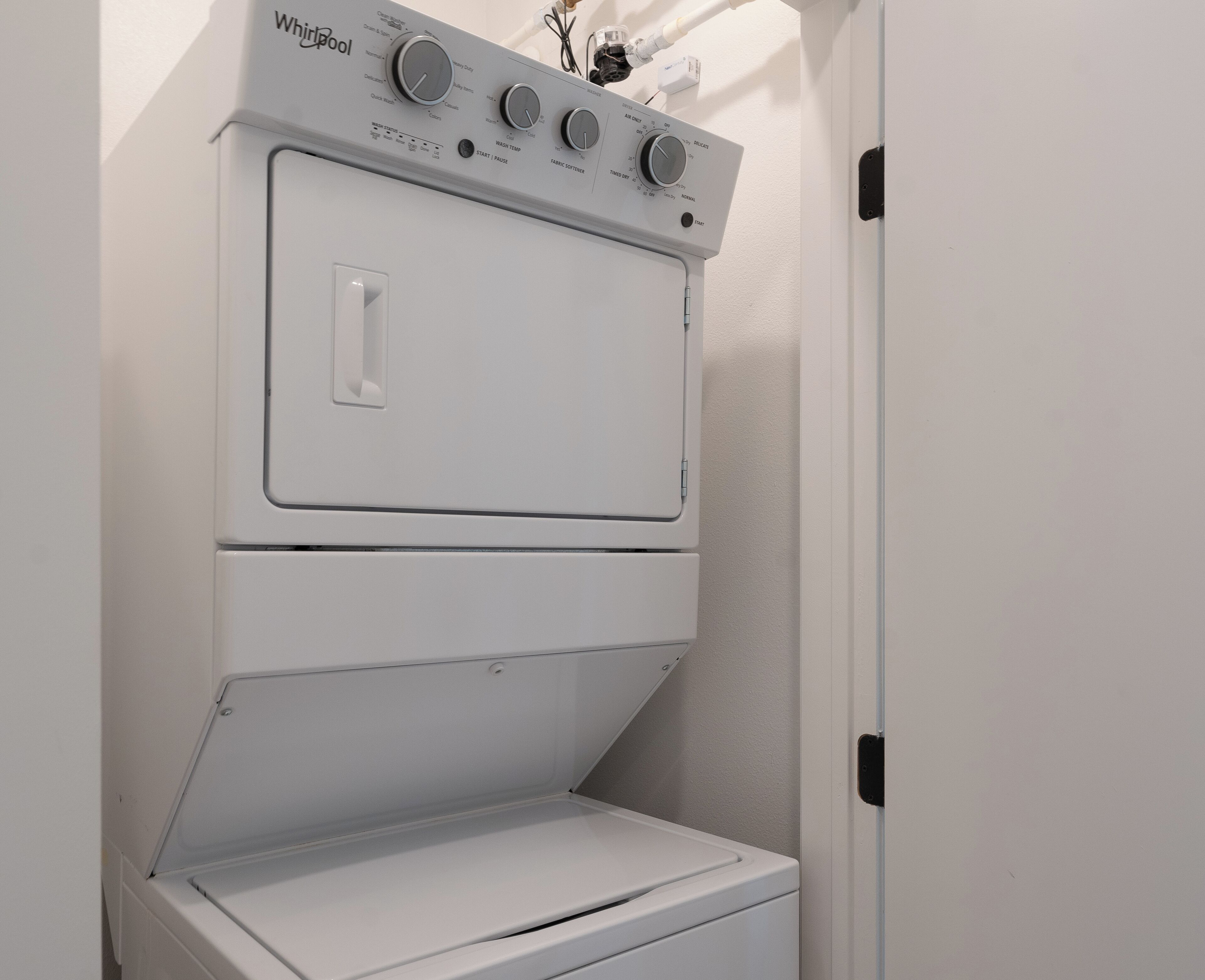 A compact, white, wall-mounted washer and dryer unit with control knobs and a door handle.