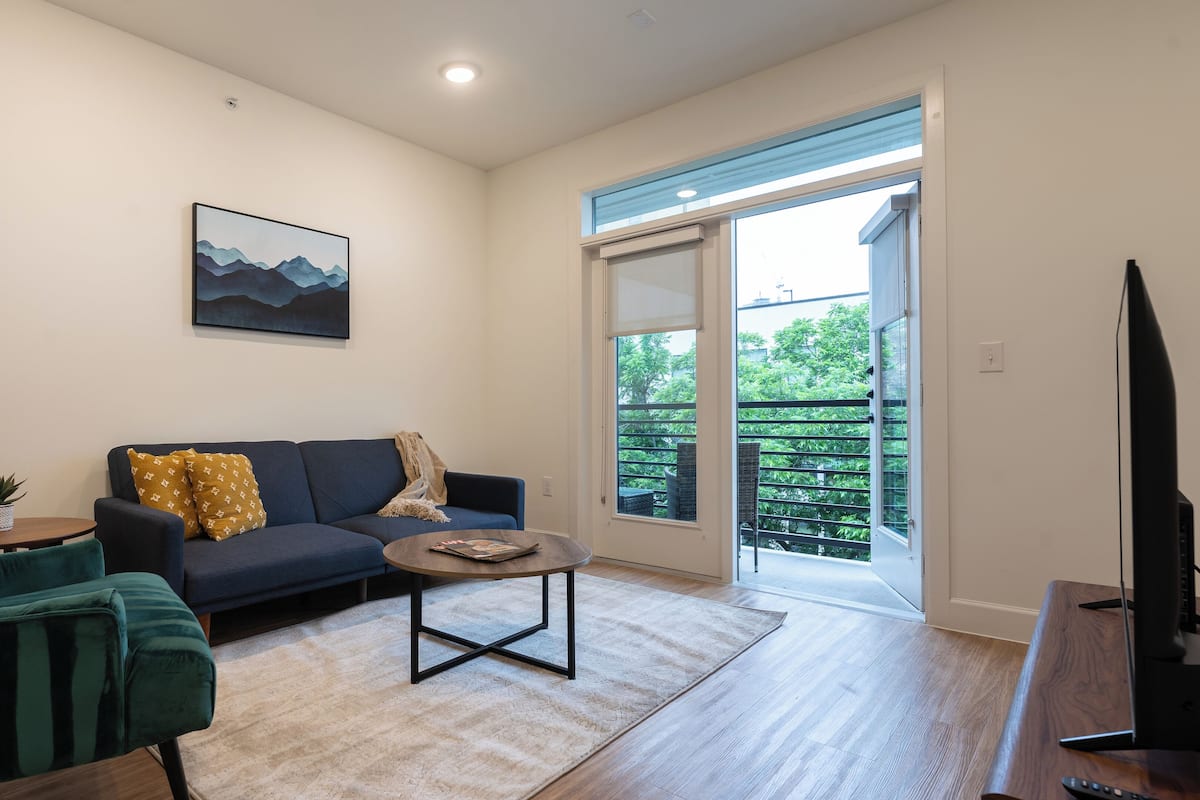 A modern living room with a sofa, armchair, coffee table, and a television.