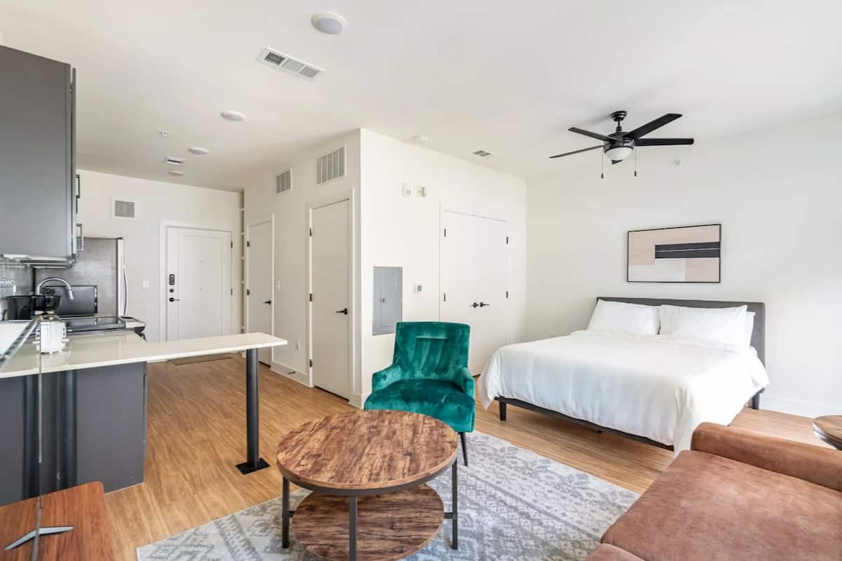 A modern hotel room with a bed, a desk, a chair, and a ceiling fan.