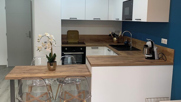 A modern kitchen with white cabinets, a wooden countertop, and a built-in microwave.