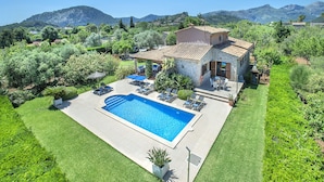 Une maison avec une piscine, du mobilier d’extérieur et un jardin bien entretenu.
