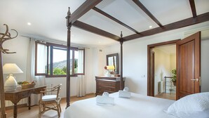 Une chambre à coucher avec un lit à baldaquin, un bureau en bois avec une lampe, une chaise et une commode.