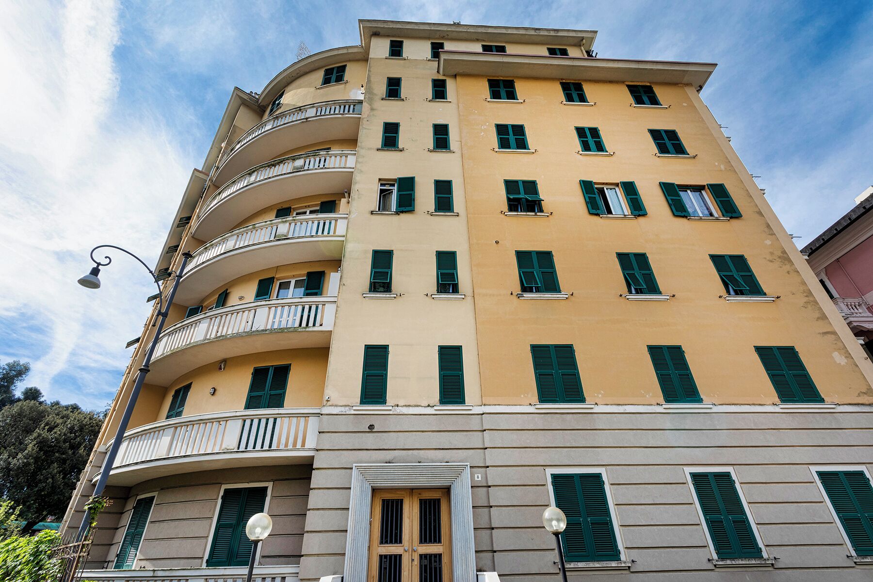 A multi-story building with balconies, a door, and a street lamp.