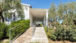 A covered outdoor staircase leading to a building with a white facade, surrounded by olive trees and greenery. - ClickSardegna Villa Celeste: Countryside Deluxe near the beaches of Sardinia (Alghero)
