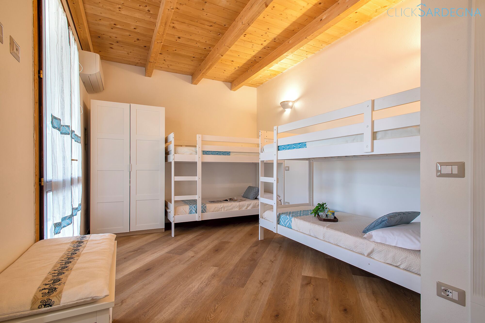 A bedroom with two bunk beds, a wardrobe, and a bench.