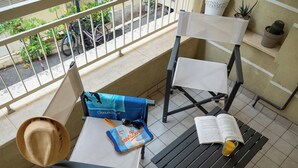 A balcony with two chairs, a bench, a hat, a bag, sunglasses, a book, and a glass of juice. - Souvenir 7 - Two Bedroom Apartment, Sleeps 6 (Gabicce Mare)