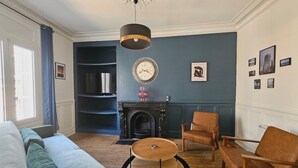 A living room with a blue wall, a fireplace, a round wooden coffee table, and a green sofa. - Le Galliéni Hyper Centre  (Le havre)
