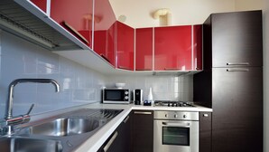 Een moderne keuken met roestvrijstalen apparatuur, een dubbele spoelbak en rode kastjes.