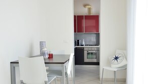 Een moderne keuken met een eethoek, met een tafel, stoelen, een fornuis en een rode kast.