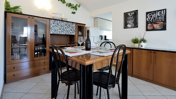Un coin repas comprenant une table en bois, quatre chaises et un buffet aux portes vitrées.