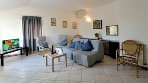 Un salon comprenant un canapé, deux fauteuils, une table basse, un téléviseur et un ordinateur portable.