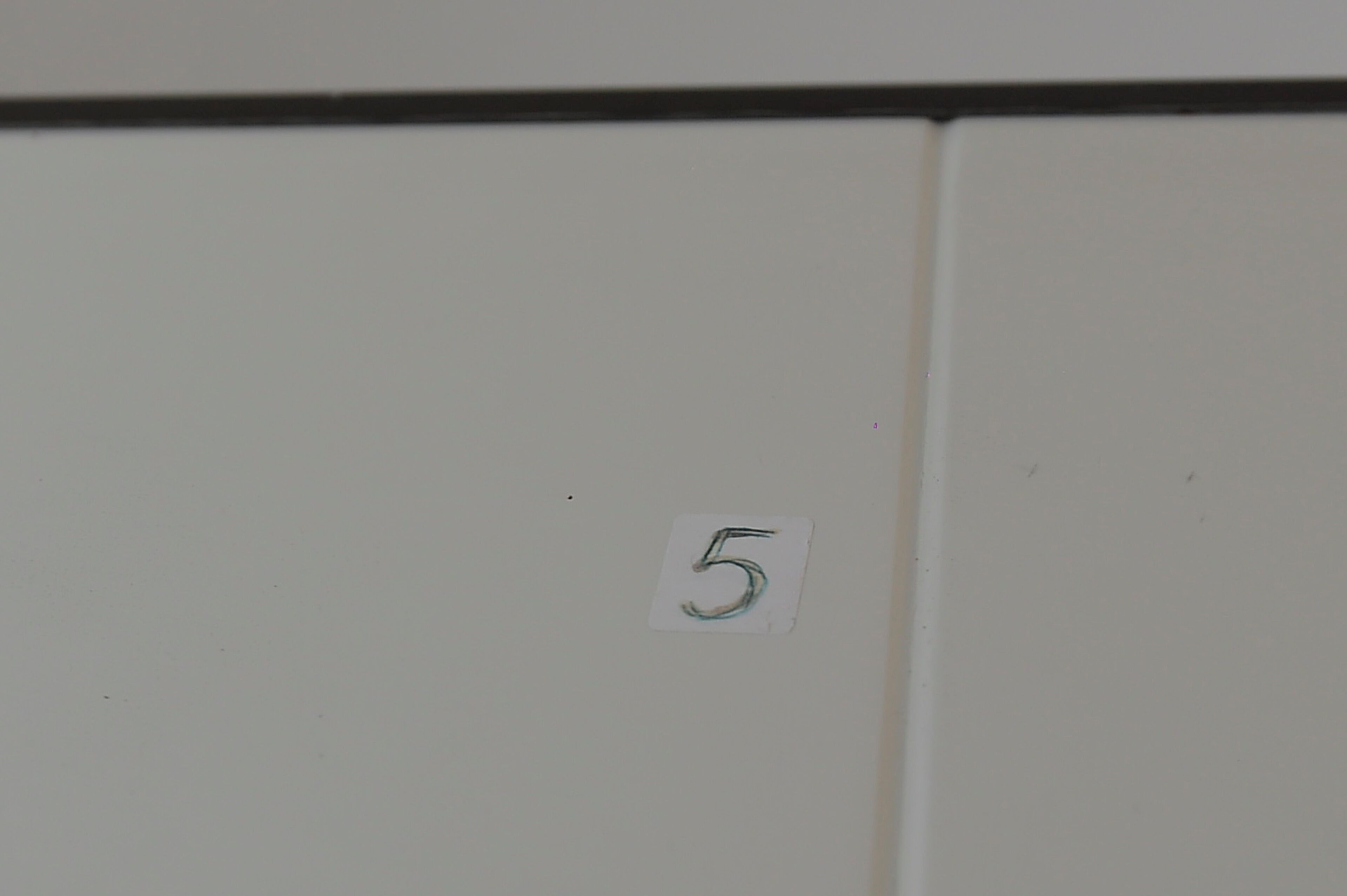 A white wall with a small white sign displaying the number 5.