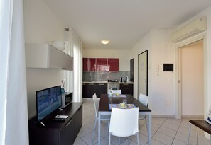 Une cuisine moderne avec des meubles de couleur sombre, un four à micro-ondes et un coin repas comprenant une table et des chaises.
