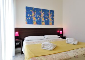 Une chambre d’hôtel avec un lit, deux lampes de chevet, un tableau et un lit soigneusement fait avec des serviettes.