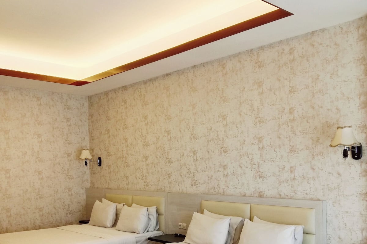 Habitación de hotel con dos camas, una silla roja y un candelabro en el techo.