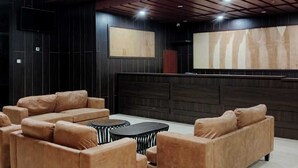 Een moderne loungehoek met leren banken, een zwarte salontafel en een grote flatscreen-tv aan de muur.