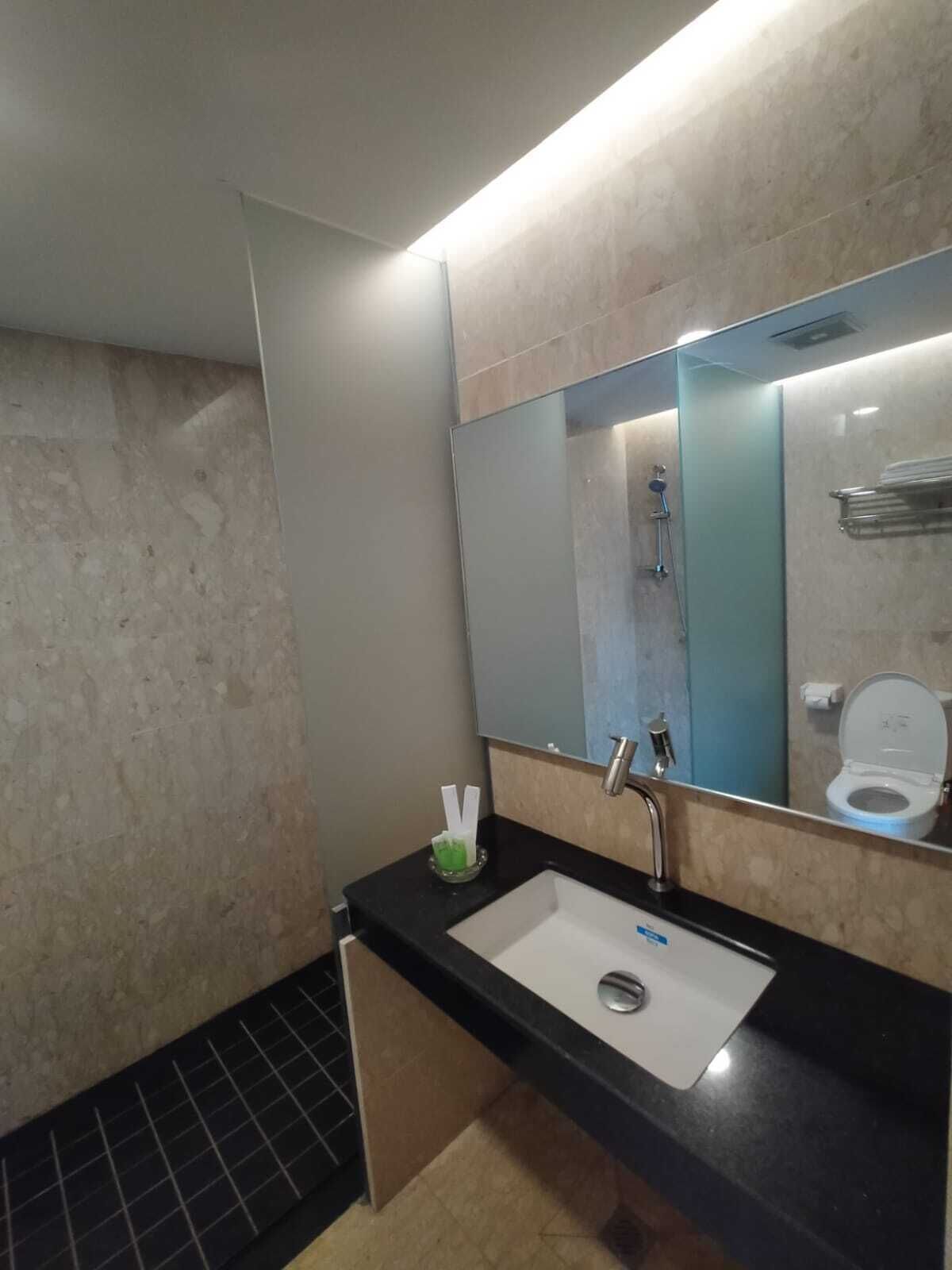 Ein modernes Badezimmer mit schwarzem Waschtisch, einem weißen Waschbecken, einem Spiegel und einer Dusche.