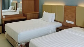 Een hotelkamer met twee bedden, een houten hoofdbord, een spiegel en een nachtkastje.