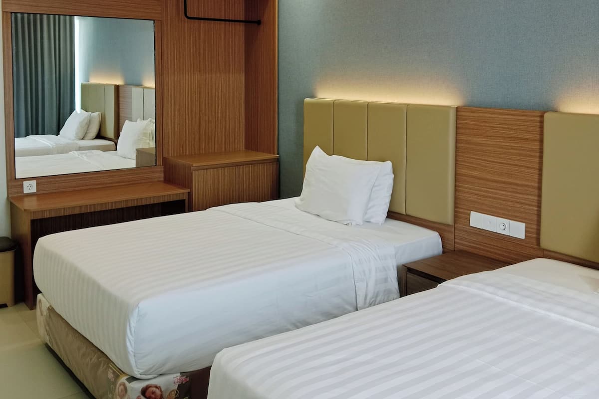 Habitación de hotel con dos camas, un cabecero de madera, un espejo y una mesita de noche.