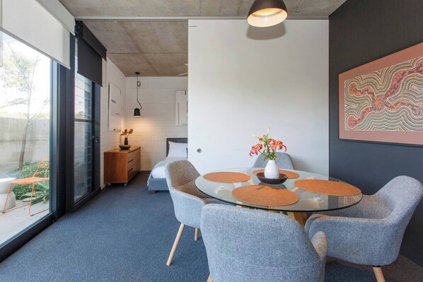 A modern meeting room with a glass table, grey chairs, and a vase with flowers.