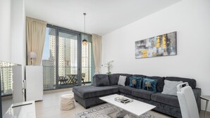 A modern living room with a grey sectional sofa, a white coffee table, and a patterned rug. - Czechin - LIV Residence (Dubai)