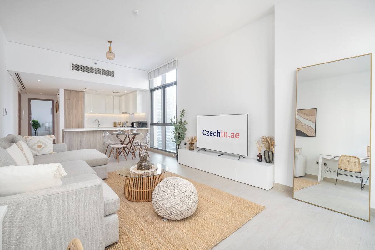 A modern living room with a sofa, coffee table, and a TV mounted on the wall.