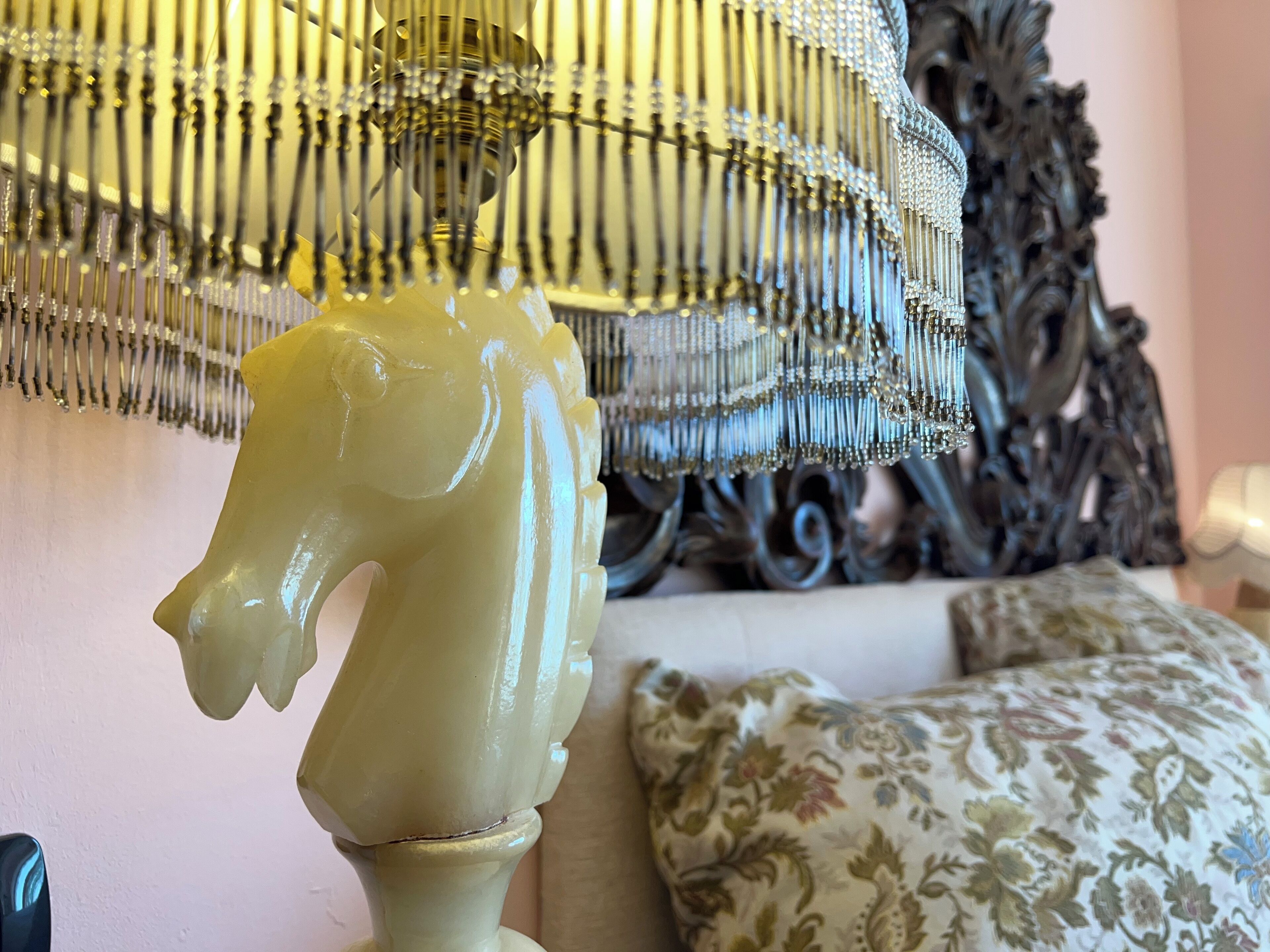 Una habitación con una lámpara decorativa con diseño de cabeza de caballo, un sofá estampado y un espejo ornamentado.