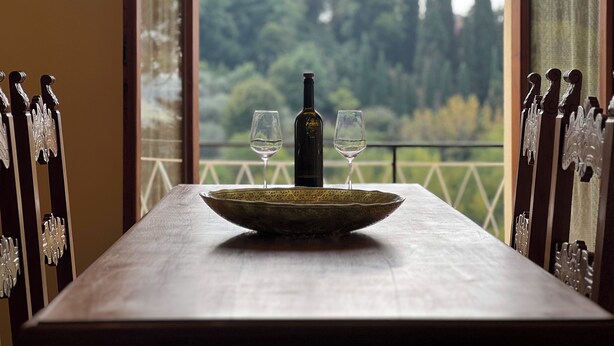Una mesa con una botella de vino y dos copas, frente a un paisaje natural.