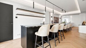 Een moderne keuken met een centraal kookeiland, barstoelen en hanglampen.