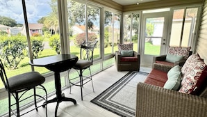 A sunroom with large windows, a ceiling fan, a dining table, and a sofa. - Beautiful Bungalow - 3/2 w/ Golf Cart in The Village of Liberty Park SMALL DOG Accepted - Max 1x 20-25lbs (The Villages)