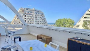 A rooftop terrace with a table, chairs, a small bench, and a cabinet. - Studio with Parking and Sea View (La Grande-Motte)