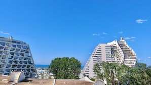 A modern building with unique architecture, a marina with boats, and a clear blue sky. - Studio with Parking and Sea View (La Grande-Motte)