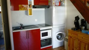 Eine kleine Küche mit Mikrowelle, Backofen und Waschmaschine.