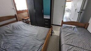 A bedroom with two single beds, a wardrobe, a mirror, and a door leading to a balcony. - Seafront T2 with AC and parking (Port-la-Nouvelle)