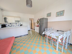 A compact kitchen with a refrigerator, microwave, and tiled backsplash.