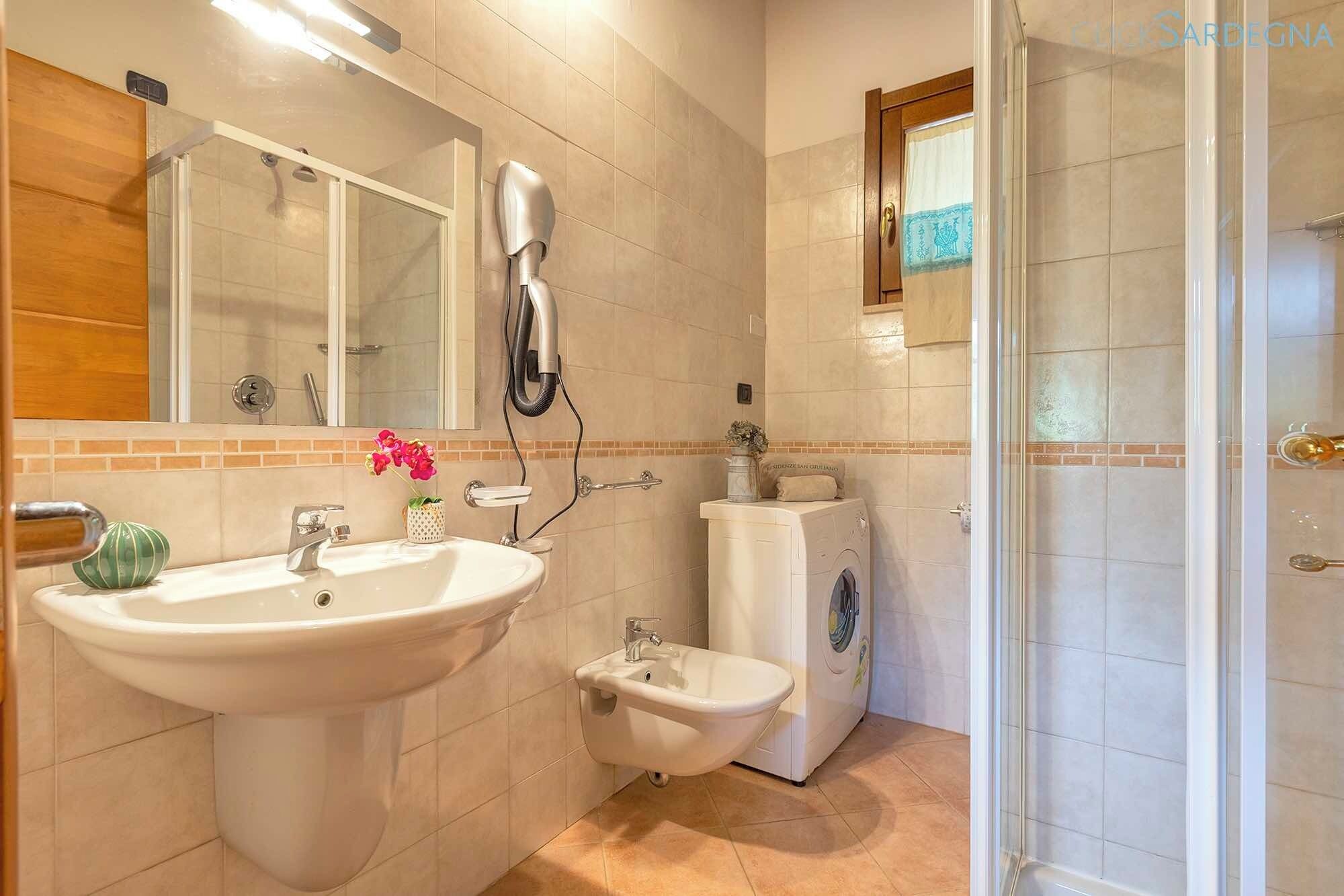 Un baño con lavamanos, bidé y un secador de pelo montado en la pared.