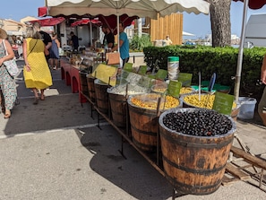 Un marché de rue où l’on vend des olives et d’autres produits alimentaires dans des barils en bois.