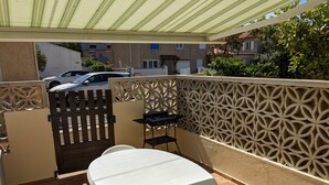 A covered outdoor patio with a table and benches, a gate, and a decorative wall. - Charming 2-Bedroom Villa with AC, 400m from Beach, Sleeps 5/6 (Port-la-Nouvelle)